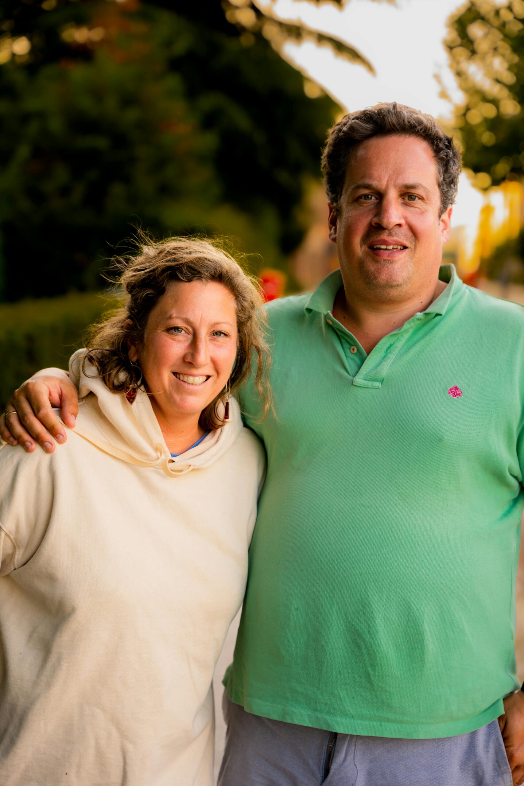 A happy couple smiling and embracing while standing outdoors during sunset.